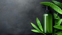 Green cosmetic bottle with pump dispenser surrounded by fresh aloe vera leaves on dark textured background for natural skincare and beauty products.