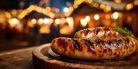 Grilled bratwurst sausages on wooden board with warm bokeh lights creating cozy evening atmosphere for outdoor dining and barbecue celebrations.