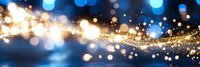 Abstract festive background with glowing golden and blue bokeh lights, sparkling magical dust trail and blurred glitter effect creating dreamy atmosphere.