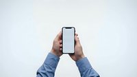 Hands holding smartphone with blank white screen mockup on white background for app presentation and digital marketing campaigns.