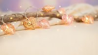 Decorative copper wire string lights with intricate metal leaf ornaments creating warm ambient lighting for home decor and festive celebrations.
