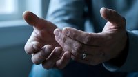 Businessman in suit with open cupped hands gesture showing protection, support and care in professional office environment.