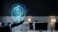 Business hand presenting glowing bank shield hologram with pillars symbol for financial security and protection in modern office environment.