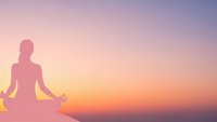 Woman silhouette meditating in lotus pose against colorful sunset sky. Peaceful yoga practice for mindfulness, wellness and spiritual balance concepts.