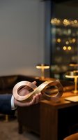 Businessman holding infinity symbol made of white and gold ribbons in modern office setting with warm bokeh lighting.