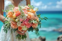 Bride holding luxurious coral and cream rose bouquet against turquoise ocean backdrop, featuring garden roses, eucalyptus greenery and delicate white blooms.