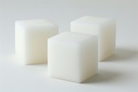 Three white sugar cubes arranged on light background with soft shadows, minimalist composition for food and beverage industry or healthy lifestyle concepts.