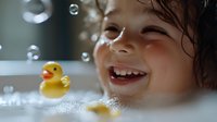 Happy toddler girl laughing during bath time with rubber duck toy and soap bubbles in white bathtub creating joyful childhood memories at home.
