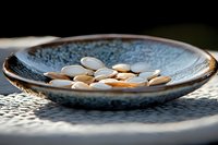 White pumpkin seeds scattered in rustic ceramic blue plate on lace doily, natural sunlight creating soft shadows, healthy snack food styling composition.