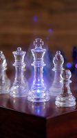 Glowing crystal chess king piece with blue light effect on wooden board, surrounded by transparent pieces, symbolizing strategy and leadership.