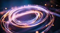 Glowing spiral light trails with purple and orange neon effects against dark background create dynamic motion and energy for technology and innovation concepts.
