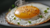 Sunny side up egg garnished with fresh herbs and black pepper on dark plate, extreme close up macro shot showing crispy edges and runny yolk.
