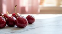 Fresh ripe red cherries with stems on marble surface in soft natural light for healthy eating and summer fruit concepts.