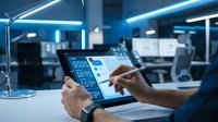 Engineer or technician with medium skin tone reviewing digital interface on tablet in modern office workspace with blue neon lighting and contemporary furniture.