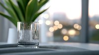 Empty glass on windowsill against blurred city lights and bokeh background at dusk, creating atmospheric minimalist composition with soft focus and depth of field.