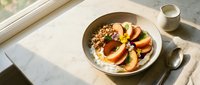 Creamy yogurt bowl topped with granola and fresh peach slices, served on marble surface with spoon and glass of milk for breakfast or healthy eating content.