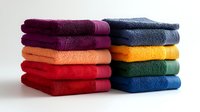 Stacks of colorful folded cotton bath towels arranged in neat piles showing texture and vibrant hues against white background for home and bathroom decor.