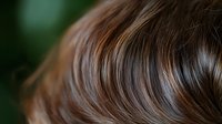 Glossy brown hair with natural highlights showing smooth texture and healthy shine for beauty and haircare concepts.