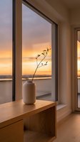 Minimalist ceramic vase with delicate branch on wooden bench by window during golden hour sunset creating warm peaceful interior atmosphere.