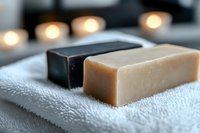 Natural handmade soap bars on white towel in spa bathroom setting with warm candle lighting for skincare and wellness routine.