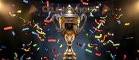 Golden trophy cup with ornate handles surrounded by colorful confetti falling against dark background with dramatic spotlight creating celebration atmosphere.