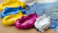Vibrant acrylic paint strokes in yellow, blue, magenta and white on artist palette, perfect for creative projects and artistic designs.