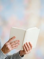 Mature adult male with light skin tone holding open blank white book against soft blurred background, reading or studying literature for education and knowledge concepts.