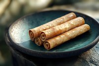 Freshly baked cinnamon roll sticks served on turquoise ceramic plate, close up view with selective focus and natural lighting for food photography.