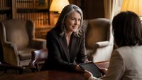 Professional mature Caucasian businesswoman in dark suit having meeting with colleague in elegant office library setting with warm lighting.