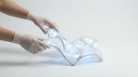 Hands in latex gloves holding transparent plastic waste material for recycling and environmental sustainability concept.