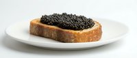 Slice of toasted bread topped with caviar served on white plate, luxury food ingredient for gourmet cooking and fine dining presentations.