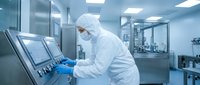Scientist in protective suit operating control panel in sterile pharmaceutical laboratory cleanroom for drug manufacturing and quality control processes.
