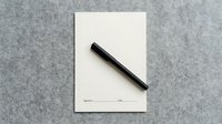 Blank signature form with black pen on gray felt surface, ready to sign a contract or agreement document.