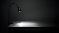 Desk lamp illuminating empty workspace surface in dark room, suitable for office, study, and professional design projects.