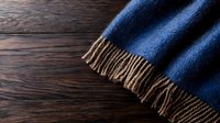 Luxurious navy blue wool scarf with brown fringe tassels on dark wooden background. Soft winter accessory showing texture and warmth detail for fashion and lifestyle.