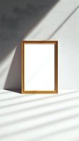 Empty golden frame on white wall with natural sunlight and shadow overlay creating minimalist composition for mockup and design presentation.