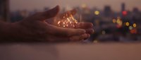 Hands cupping glowing magical lights against blurred city background at dusk, symbolizing hope, dreams, protection and spiritual energy for wellness concepts.
