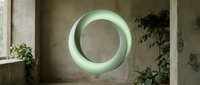 Glowing neon circle light installation on concrete wall with climbing plants and natural daylight from window, modern interior design element.
