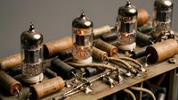 Vintage vacuum tubes and electronic components on wooden surface for retro technology and audio equipment restoration projects.