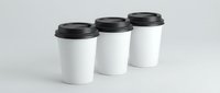 Three white disposable coffee cups with black lids arranged in row on clean background for cafe branding and takeaway beverage marketing materials.