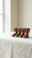 Wooden blocks spelling PLAN on stacks of golden coins representing financial planning, investment strategy, and wealth management for business success.