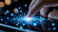Finger touching digital tablet screen creating magical blue light effect with glowing particles and bokeh lights on dark background. For technology concepts.