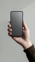 Hand holding modern smartphone with blank black screen against neutral background for mockup and app presentation purposes.