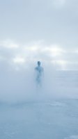 Solitary figure standing in dense fog on frozen landscape, creating ethereal and mysterious atmosphere for conceptual and editorial projects.