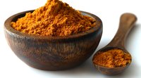 Ground turmeric powder in rustic wooden bowl and spoon against white background, vibrant orange spice for cooking, natural medicine and wellness.