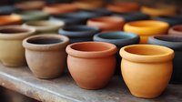 Handmade ceramic pottery bowls and cups in earthy tones displayed on wooden surface. Traditional clay vessels showcase artisan craftsmanship for home decor.