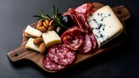 Gourmet charcuterie board with assorted cheeses, cured meats, nuts and herbs on wooden cutting board for entertaining and appetizer presentations.