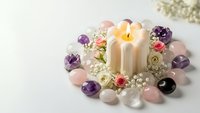 Healing crystals arranged in circle with burning candle, roses and baby's breath flowers for meditation, spiritual wellness and energy cleansing rituals.