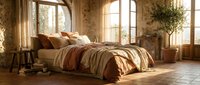 Cozy bedroom with warm sunlight streaming through large windows, featuring a bed with layered bedding in earth tones, rustic stone walls, wooden floors, and potted plants for a serene, inviting retreat.