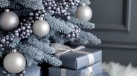 Elegant silver Christmas ornaments and frosted pine branches with wrapped present in gray and silver tones create luxurious holiday atmosphere. Modern festive decor.
